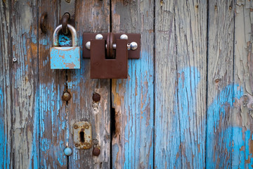 two different locks on old wooden garage door, peeling paint, in