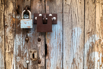 two different locks on old wooden garage door, peeling paint, in Warsaw, Poland
