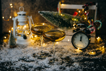 Photo of two champagne glasses on blurred background with Christmas tree, lantern, clock
