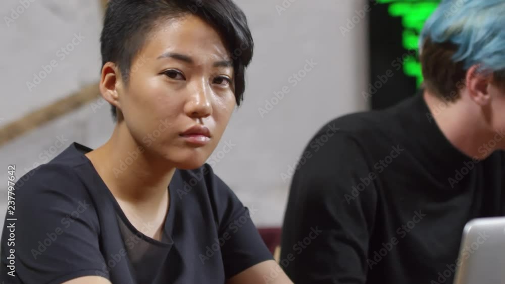 Poster portrait of young asian woman sitting at desk, using laptop computer and smiling at camera during pr