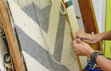 weaving and manufacturing of handmade carpets closeup. women's hands weave a carpet. A woman's hand...