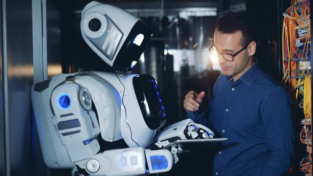 Programmer and a robot work at a data center, close up.