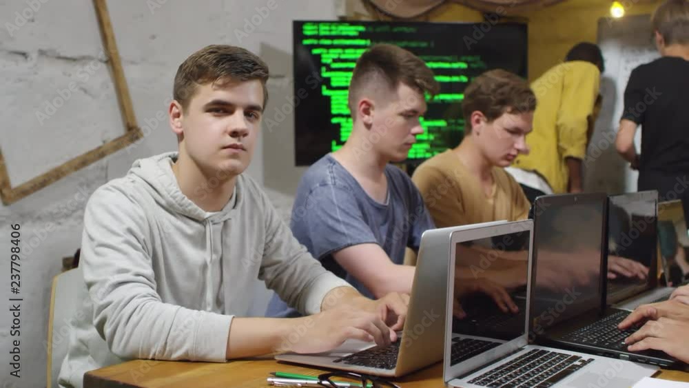 Poster portrait of young caucasian man sitting at desk and using laptop computer during programming worksho