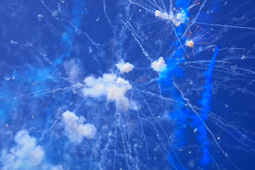 Fireworks explode, smoke in the blue sky