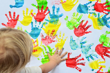 Little girl imprints multicolor hands on white background