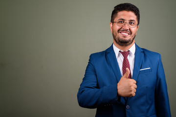 Bearded Persian businessman wearing suit against colored backgro