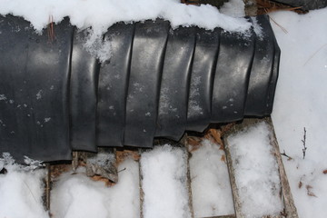 roll of black plastic covered with snow