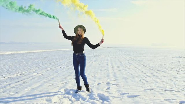 Woman dancing with colored smoke bombs
