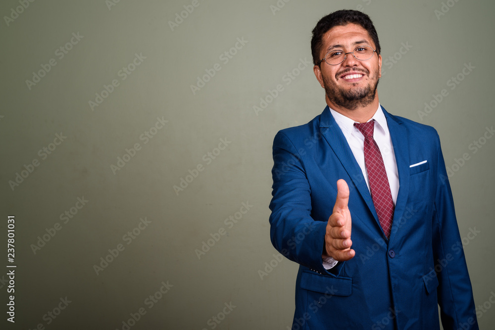 Wall mural bearded persian businessman wearing suit against colored backgro