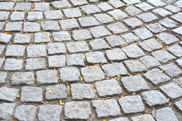 Close up outdoor view of the surface of a paved road. Pattern of grey granit cobblestones. Mosaic and geometric design. Abstract image with repetitive shapes and lines.