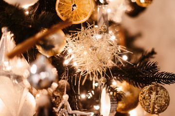 Merry Christmas and Happy New year Holidays! Decorating the Christmas tree indoors. Macro or close picture of xmas tree decorated with orange and carnival mask. Gift box background for 2019 gift card