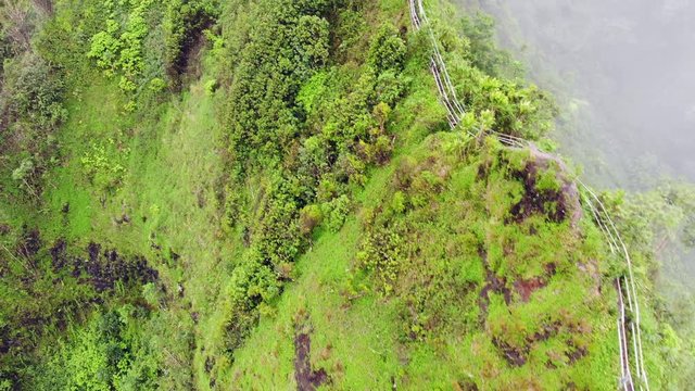 Aerial view of Stairway to Heaven (Haiku Stairs) in Hawaii with stairway on a cliff disappearing into the clouds