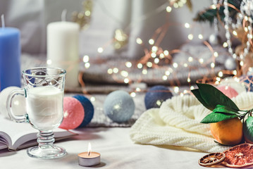 Romantic winter and New Year's style interior view with a candle, book, garland and glass of milk