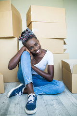 Moving in. Charming young african girl standing on her knees on the floor and smiling at the camera...