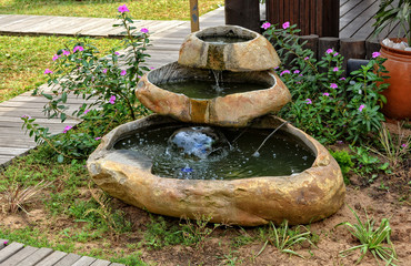 Small garden fountain with flowing water. Beautiful landscape. Calmness.