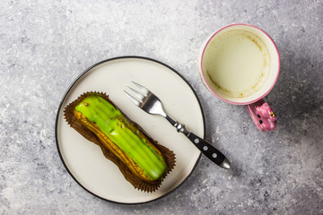 eclairs on white plate with cup of latte coffee on grey table. Top view.