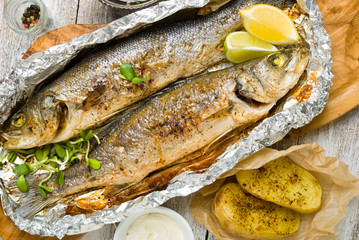 Fresh baked fish sea bass (Dicentrarchus labrax) on a light wooden background