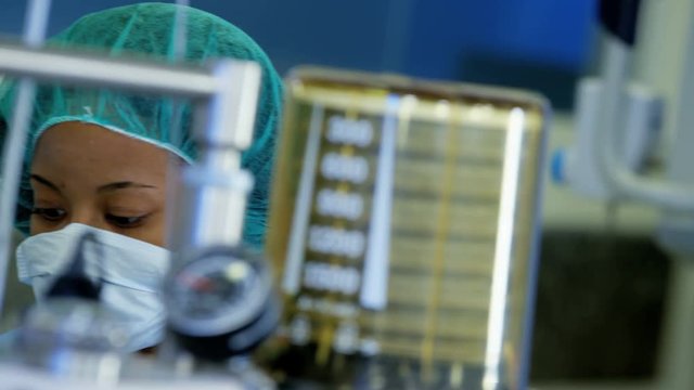 Female Multi ethnic Anesthesiologist in healthcare training hospital viewing monitoring anesthesia equipment during operation 