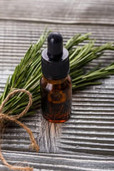 Rosemary essential oil on a gray wooden rustic background