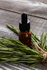 Rosemary essential oil on a gray wooden rustic background