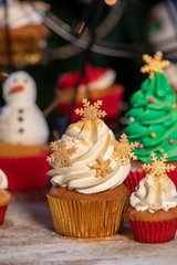 Various colorful Christmas cupcakes with christmas tree on wood table