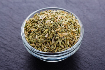 Essential oil of fennel seeds on a dark stone background