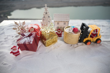 Miniature Gift Box by Forklift Machine on snow ,Determined Image for Christmas Holiday and Happy New Year Gift Celebration concept.