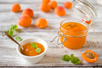 jar with homemade apricot jam on a light wooden background