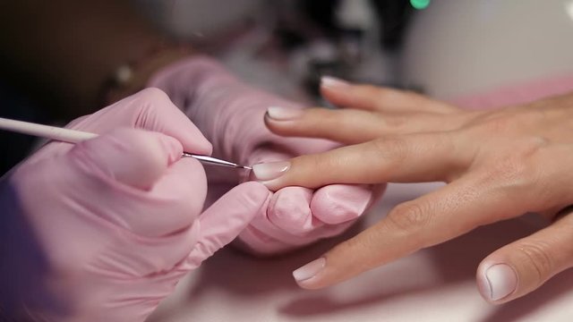 Master makes manicure with airbrush in white