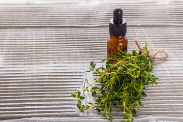 essential oil of thyme on a gray wooden rustic background