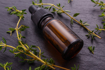 essential oil of thyme on a dark stone background