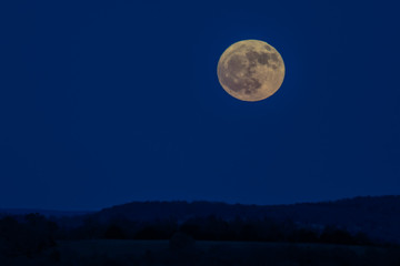 Fototapeta na wymiar Full Moon over rolling hills silhouette with blue sky