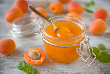 jar with homemade apricot jam on a light wooden background