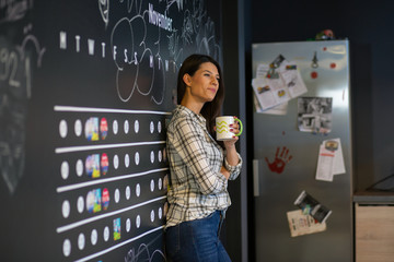 Young beautiful business woman drinking her coffee and smiling in the kitchen 