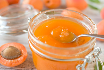 jar with homemade apricot jam on a light wooden background