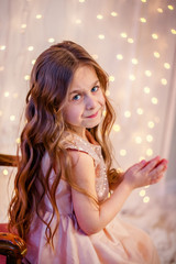 Portrait of a little girl with curly hair on Christmas Eve, the New Year will bring gifts.