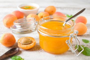 jar with homemade apricot jam on a light wooden background