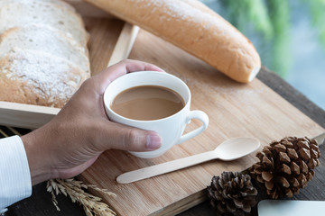 Hands of businessman holding cup of coffee and breakfast bread. Health breakfast