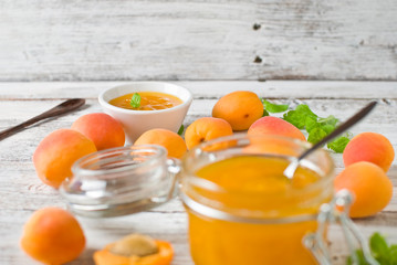 jar with homemade apricot jam on a light wooden background