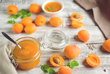 jar with homemade apricot jam on a light wooden background