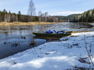 Raft on the snowy Bank of the river. Spring rafting.
