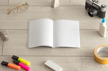 Empty notebook on wood floor with office tools nearby