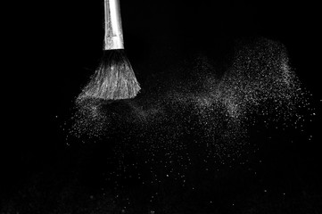 white powder splash and brush for makeup artist or beauty blogger in black background