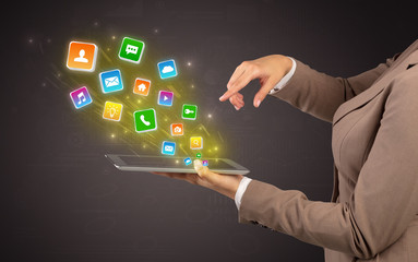Hand holding tablet and application icons falling inwards
