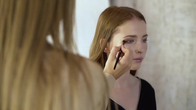 Makeup artist applies corrective shadows on the eyelids