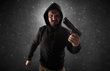 Masked armed villain in empty dark room with gun ax chainsaw mallet wrench
