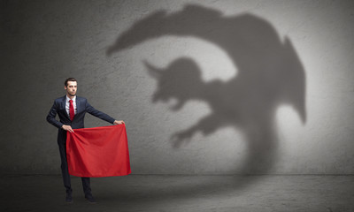 Businessman standing with red cloth in his hand and imp shadow on the background
