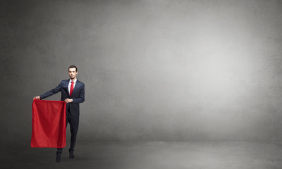Obraz premium Businessman standing with red toreador cloth in his hand in an empty room 