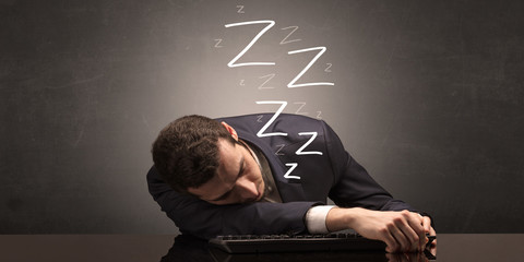 Young businessman fell asleep at the table on his keyboard concept