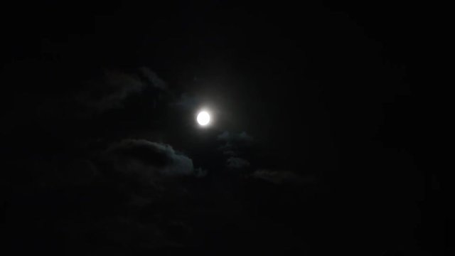 A realtime shot of the moon and clouds in the night sky.